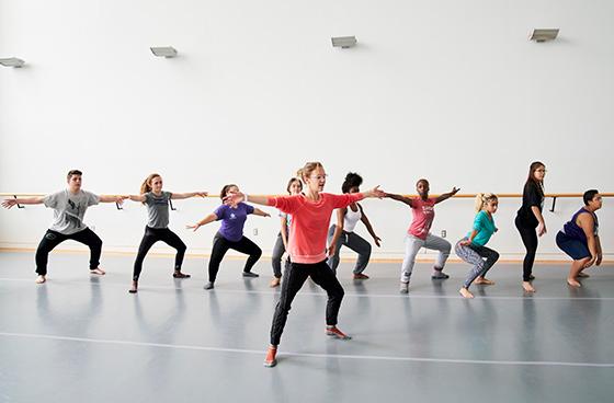 在舞蹈室上舞蹈课. Students at the balance bar following an instructor's movements.